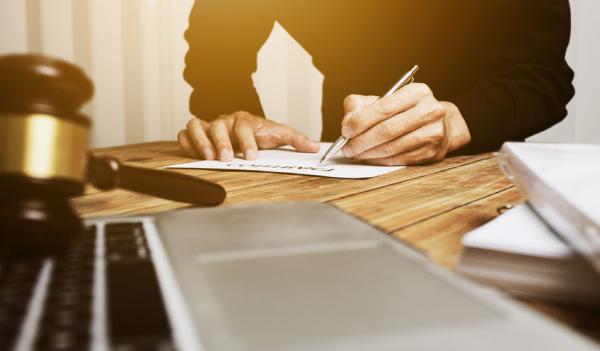 man filling out application laptop and gavel on the foreground